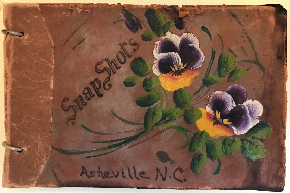 Front cover of the Edward Bobal Photograph Album. Hand painted brown leather with purple and yellow pansy flowers and leaves.  It reads “Snap Shots Asheville, N.C.”