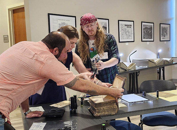 Participants examine a manuscript book with multispectural imaging.