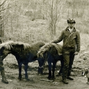A black-and-white photograph captures two men, two men, and a dog
