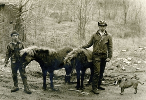A black-and-white photograph captures two men, two men, and a dog